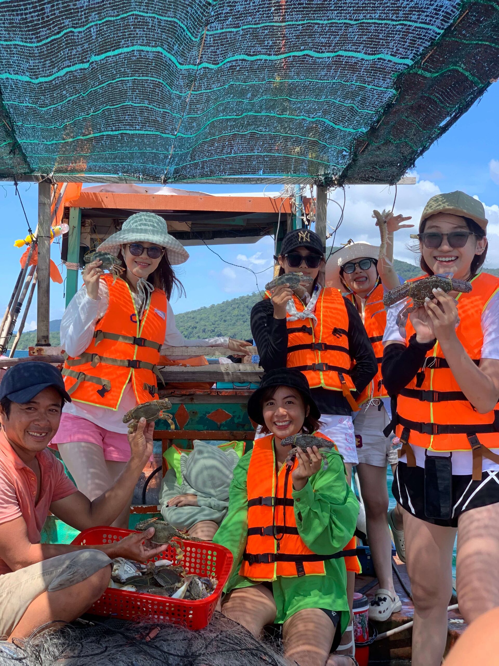 a group of people waring life jackets posing with crabs