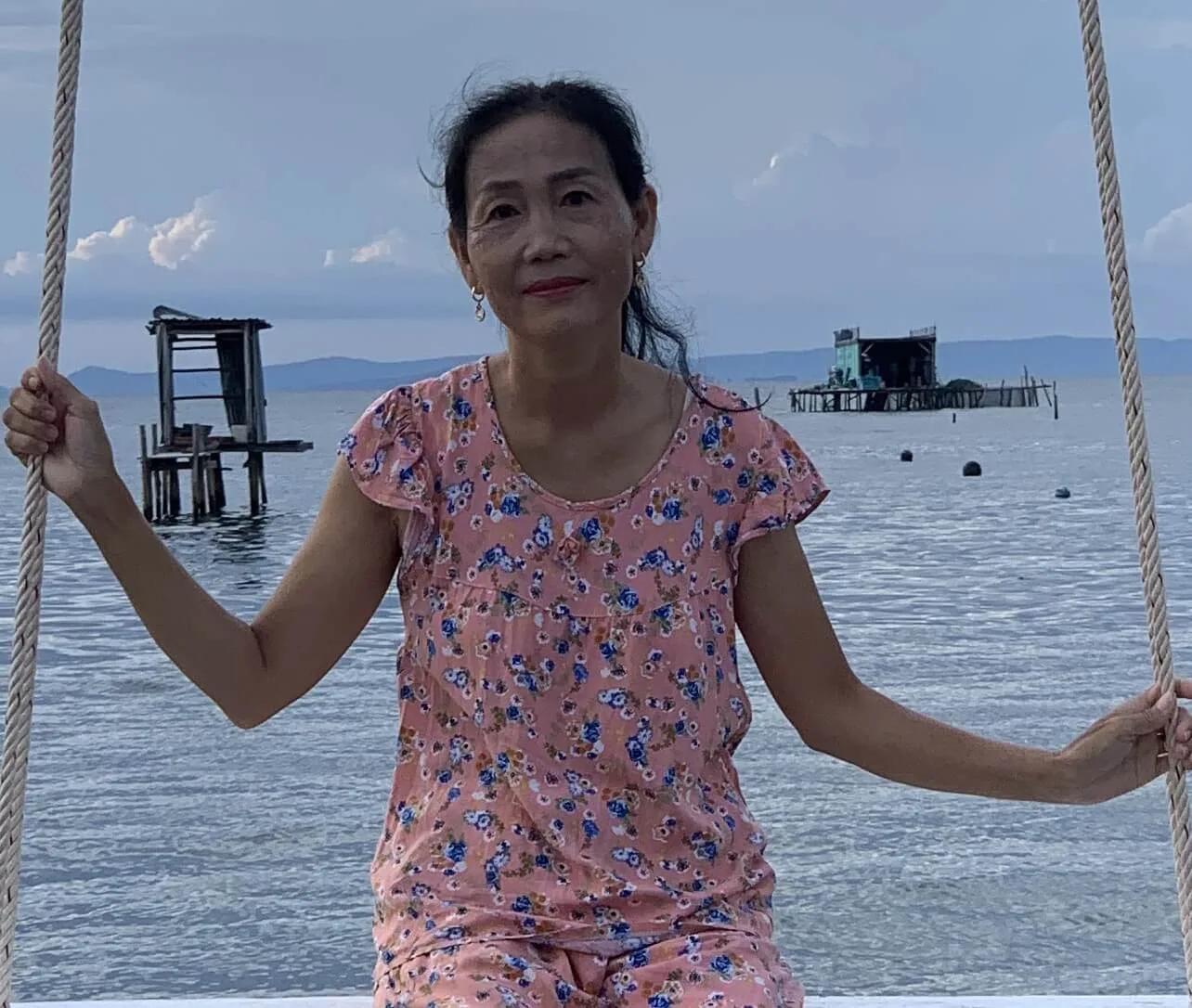 an older woman on a swing by the water