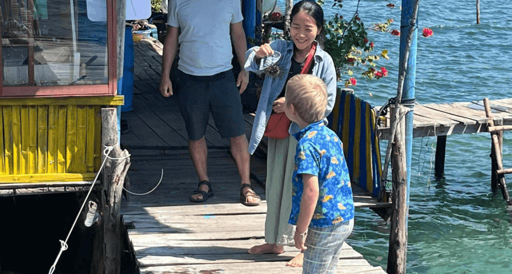 A kid is watching a woman holding a sea urchin