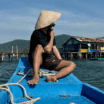 a guy on a boat with a vietnamese hat