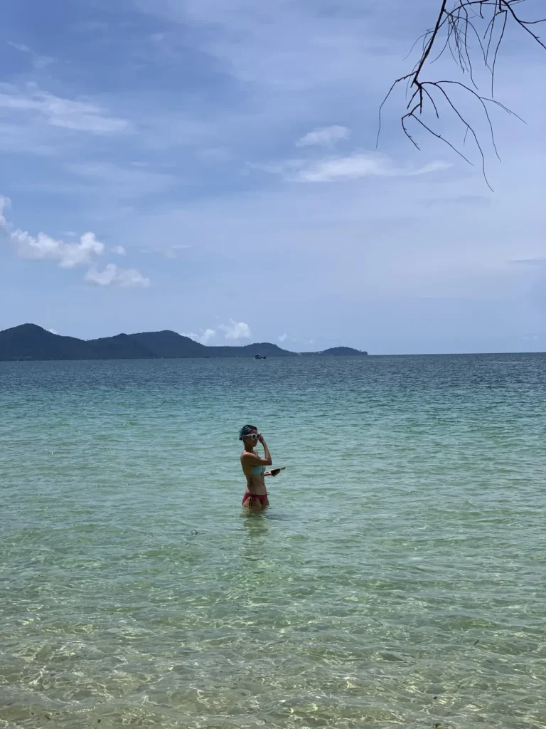 a woman knee deep in crystak clear water near starfish beach